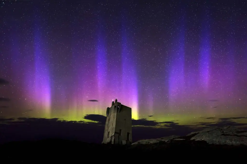 Northern lights visible behind the tower at Banba's Crown, Malin Head