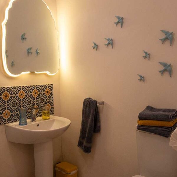 The bathroom with backlit mirror and tiled basin area