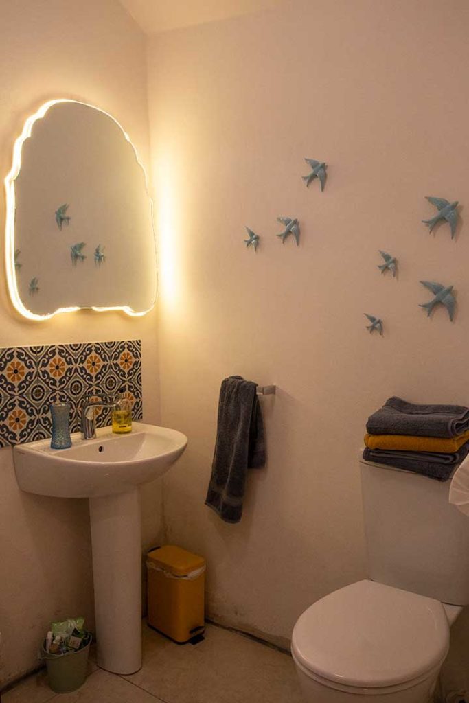 The bathroom with backlit mirror and tiled basin area